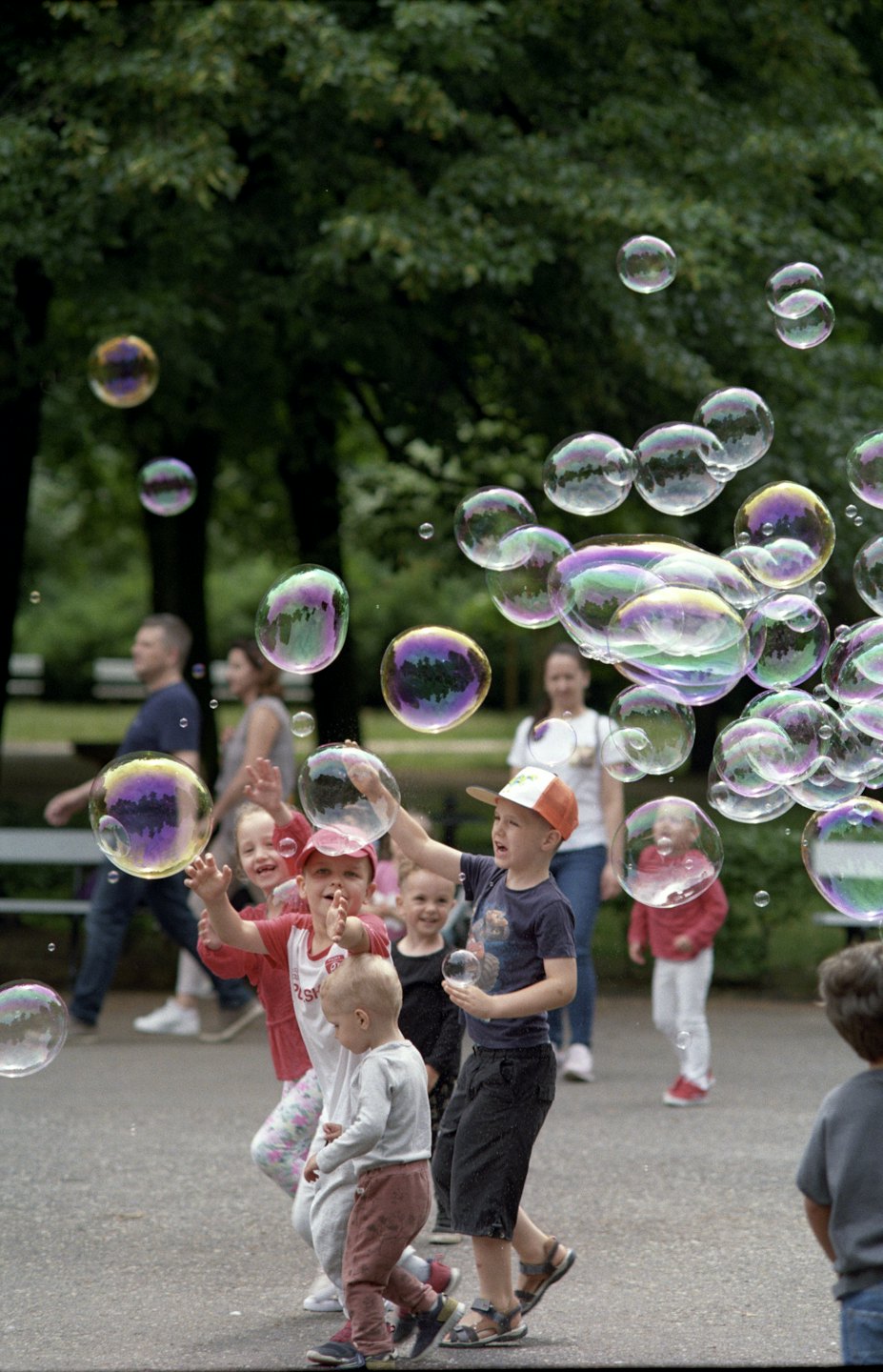 Kinder fangen fröhlich bunte Seifenblasen in einem sonnigen Park.
