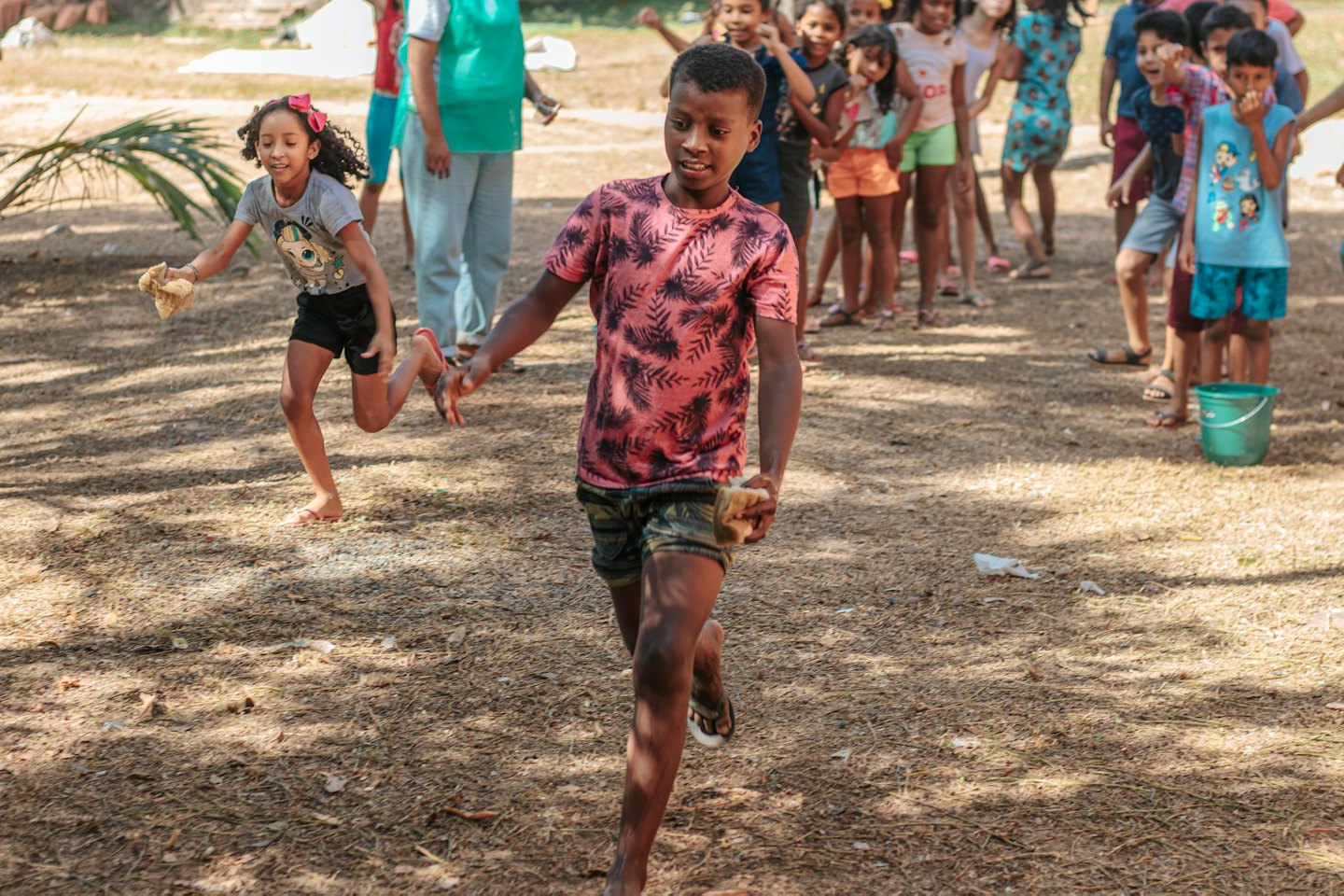 Kinder spielen ein energiegeladenes Spiel im Freien auf einem sonnigen Feldweg.
