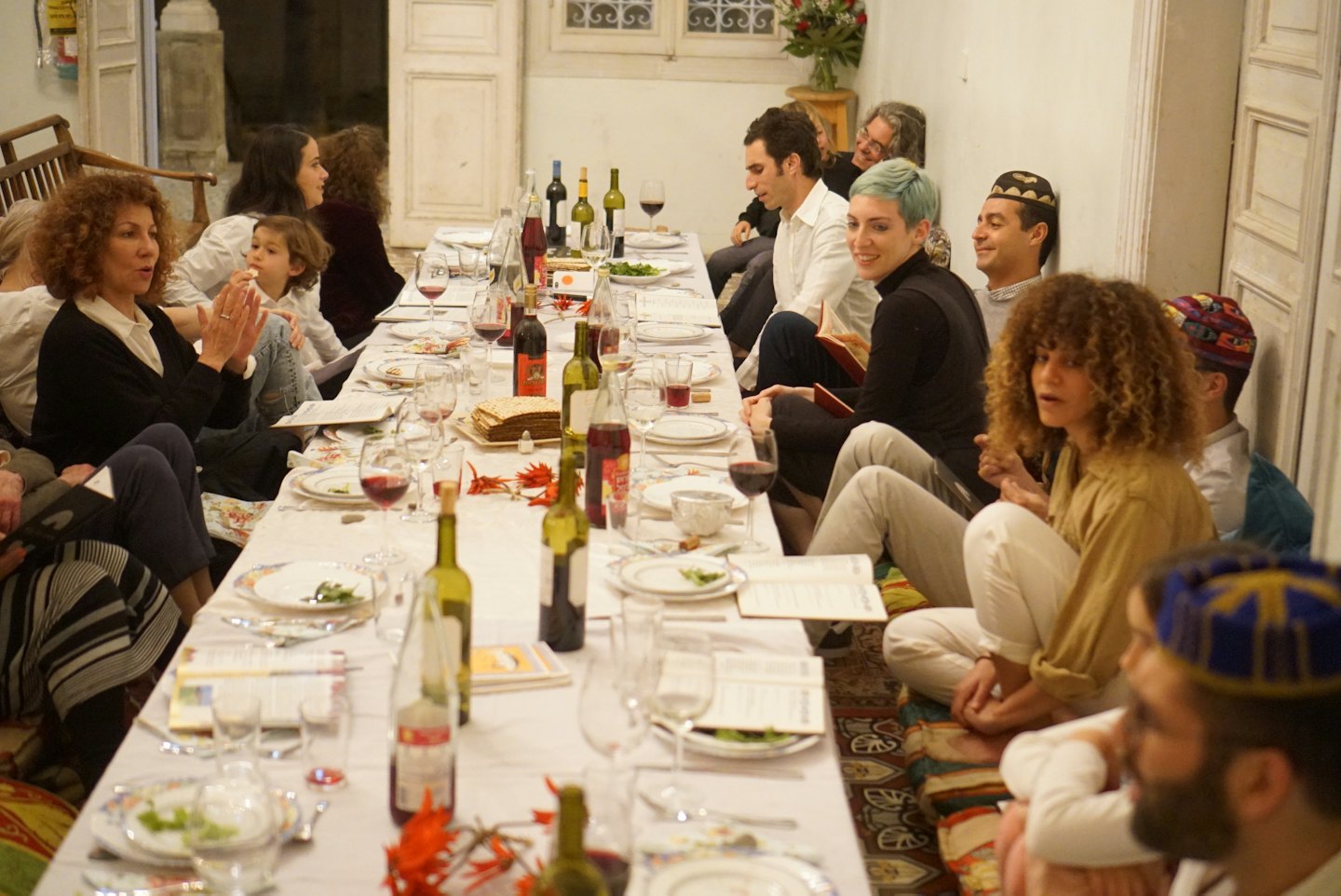 Menschen sitzen auf Bodenkissen und teilen eine Mahlzeit um einen Tisch.